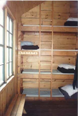 Interior of Greenleaf Hut showing wooden bunk beds, ladder, and window light