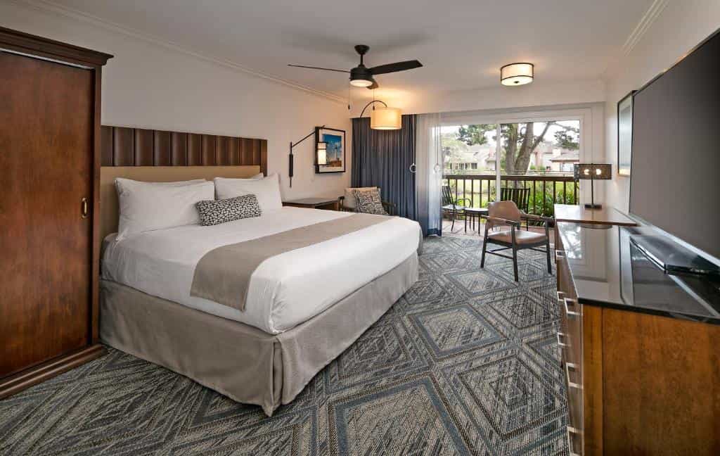 Hotel room at Half Moon Bay Lodge with king bed, balcony view, and patterned carpet