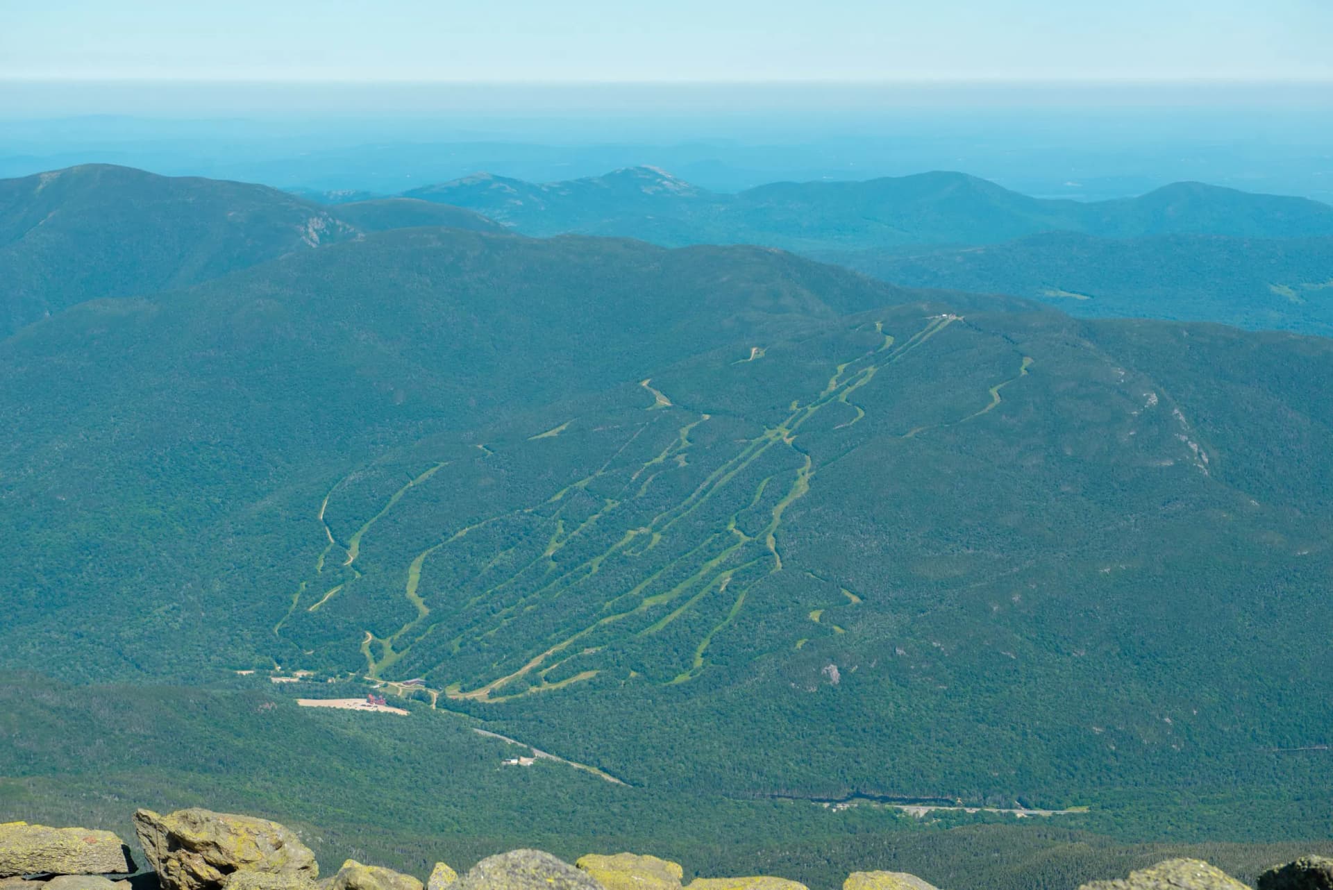 View from rocky summit over forested mountains showing ski trails at Wildcat Mountain Ski Area.