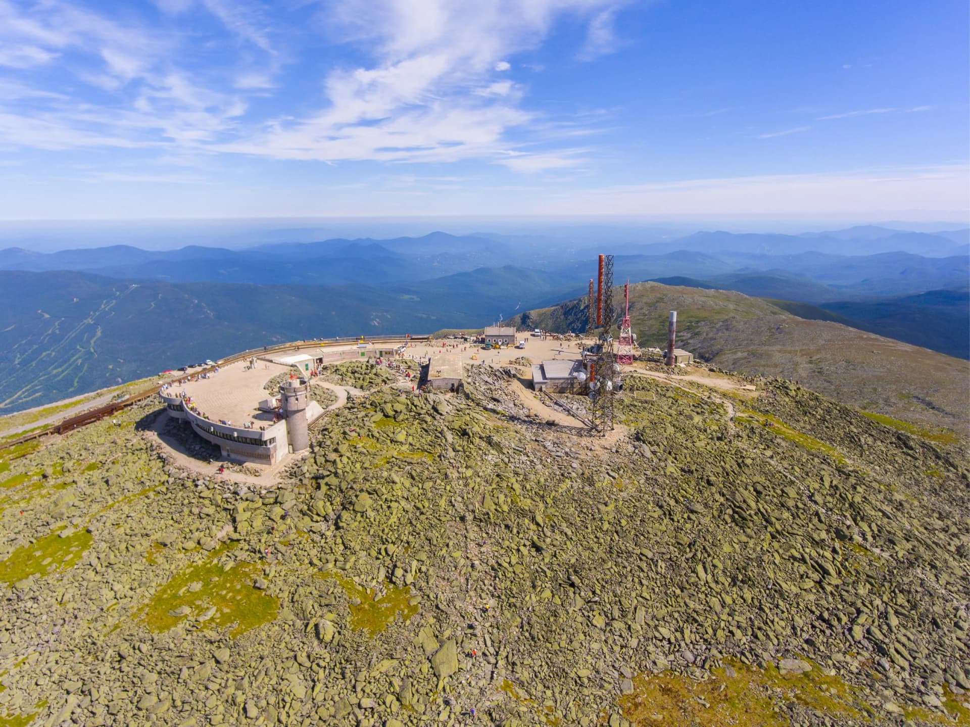 Aerial view of Mount Washington summit buildings, observation deck, and communication towers in summer.
