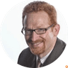 Close-up portrait of man with red hair and glasses smiling against white background