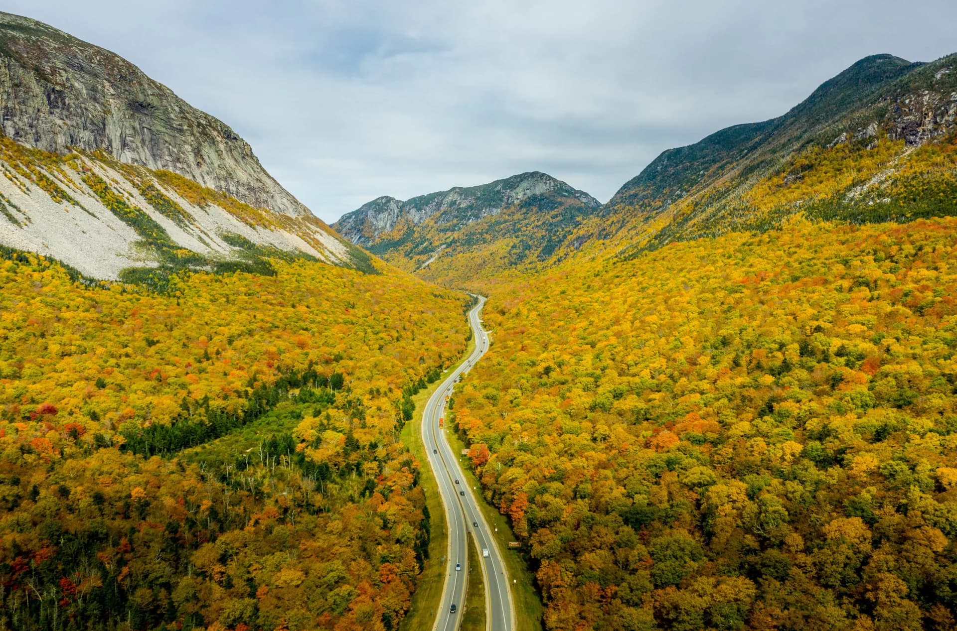Highway winding through New Hampshires White Mountains ablaze with vibrant autumn foliage.