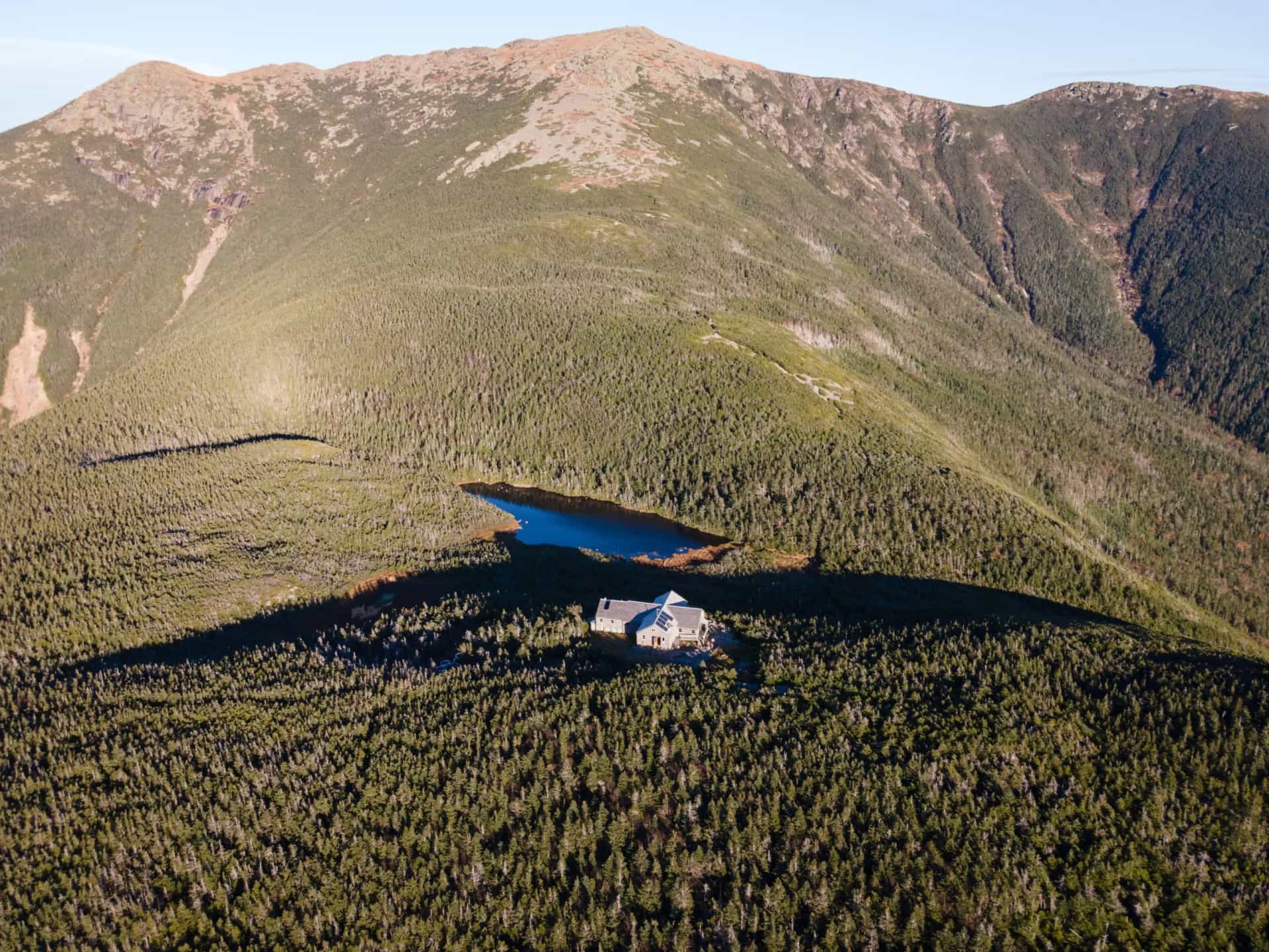 Greenleaf Mountain Hut below summit of Mount Lafayette in White Mountains, New Hampshire, with small lake.