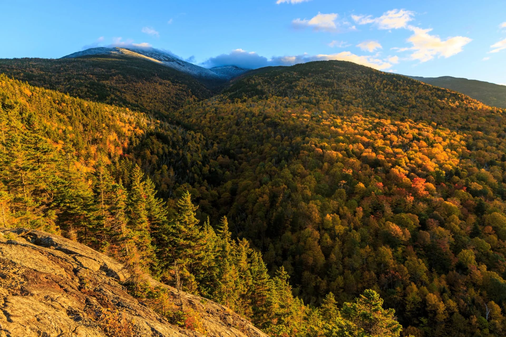 Fall foliage on Mount Madison in New Hampshire's White Mountain National Forest with snowy peaks.